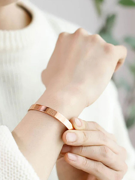 女性の手元をアップで写し、銅の質感と肌なじみの良さが分かる着用画像。