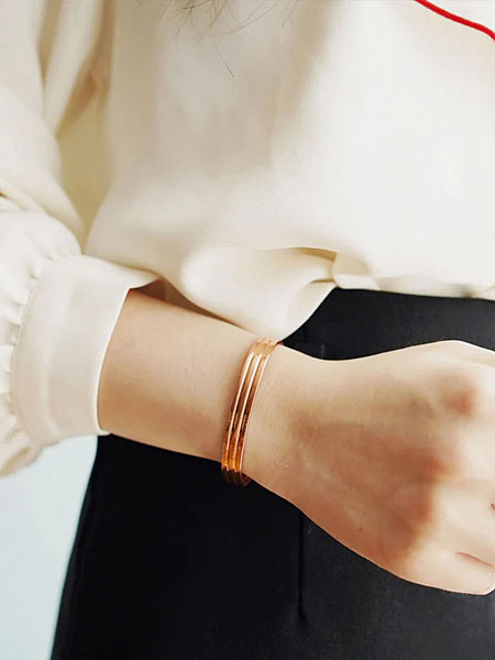 女性の手元をアップで写し、マットな銅の質感とラインの立体感が分かる着用画像。