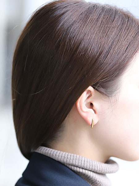 ワイズマンピアスを女性が着用している様子で、K18コーティングのやわらかなゴールドの色味が耳元になじむ画像。