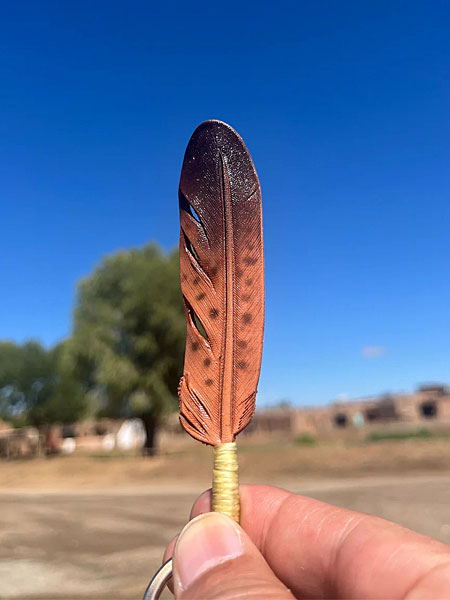 青空を背景にフェザートップを手に持ち、レザー表面の斑点模様が際立つように写した画像。