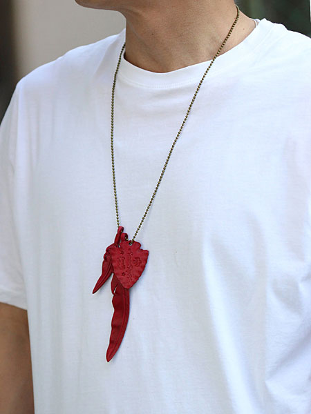 白Tシャツを着た男性の胸元アップで、レッドフェザーが映える着用イメージが分かる画像。