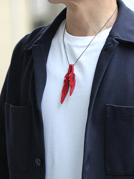 50cmチェーンで首元にバランスよく収まるレッドレザーフェザーネックレスを男性が着用している画像。