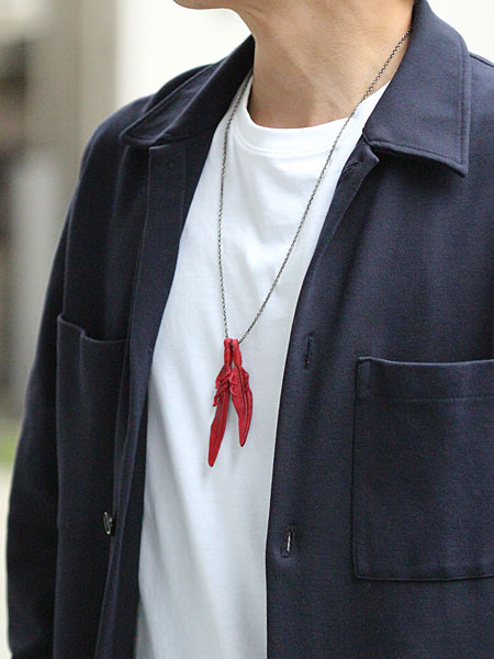 70cmチェーンで長めに着けたレッドレザーフェザーネックレスを男性が着用し、リラックス感が伝わる画像。