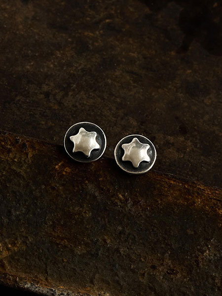 暗めの背景に置き、トルクスネジモチーフとヴィンテージ感が際立つピアスの画像。