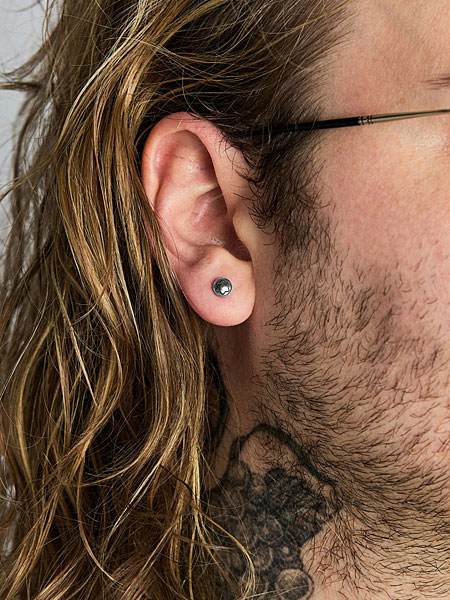 男性が着用し、耳元に自然に馴染むトルクスネジモチーフのピアスのサイズ感がわかる画像。