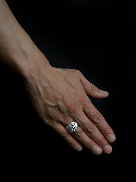 男性が薬指に着用したシグネットリングの画像で、程よいボリュームと存在感が指元で際立っています。