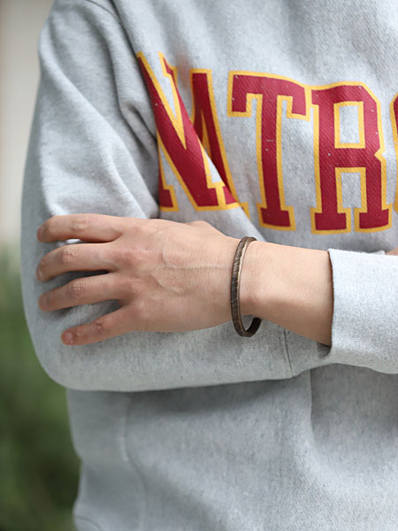 男性が真鍮バングルを着用した画像で、ワークパティナの風合いが手元にしっかり映えています。