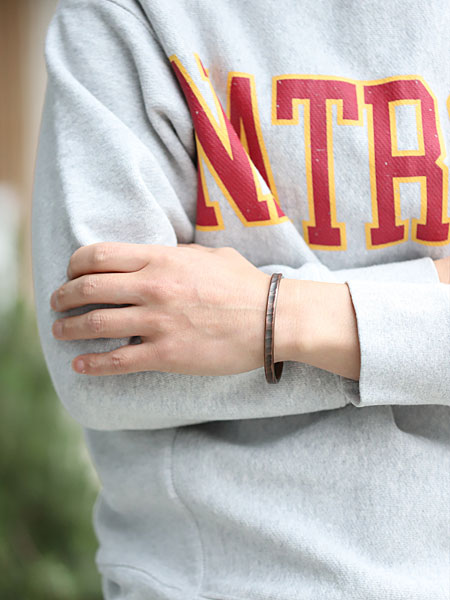 男性がバングルを着用した画像で、ワークパティナの風合いが手元にしっかり映えています。