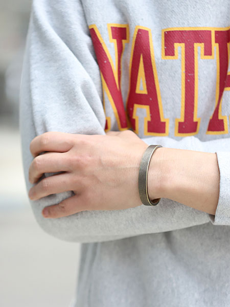 男性が真鍮バングルを着用した画像で、ワークパティナの風合いが手元にしっかり映えています。