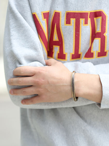 男性が真鍮バングルを着用した画像で、ワークパティナの風合いが手元にしっかり映えています。