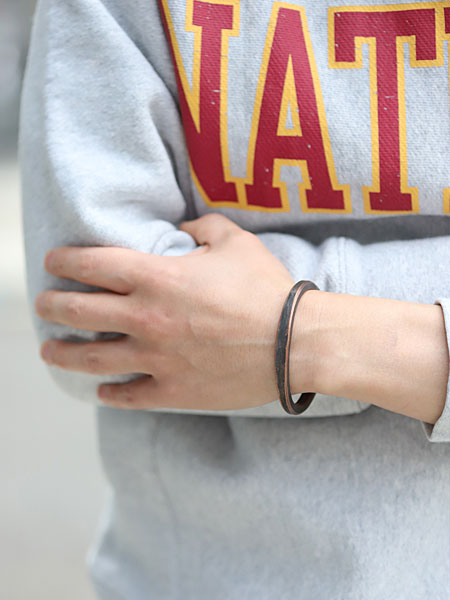 男性がバングルを着用した画像で、ワークパティナの風合いが手元にしっかり映えています。