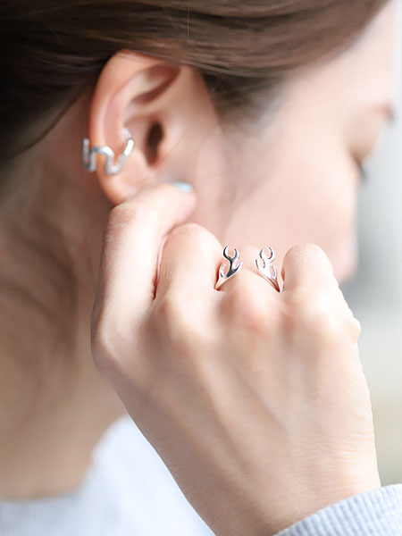 女性が薬指に鹿の角モチーフのリングを着用し、自然光の中で指もとを写した着用画像。