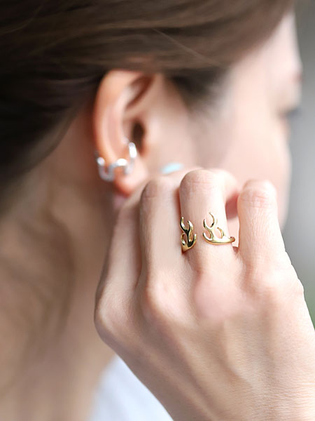 女性が薬指に鹿の角モチーフのリングを着用し、自然光の中で指もとを写した着用画像。