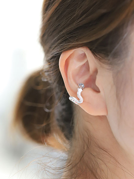 女性の耳元に白蛇モチーフのイヤーカフを着用したアップの画像。