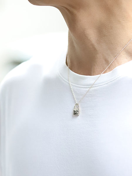 男性が着用した様子を写した、小ぶりな南京錠トップがさりげなく映えるネックレスの着用イメージ画像。