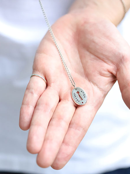 ペンダントトップを手のひらに乗せて写した、小ぶりで上品なサイズ感がわかるネックレスの画像。