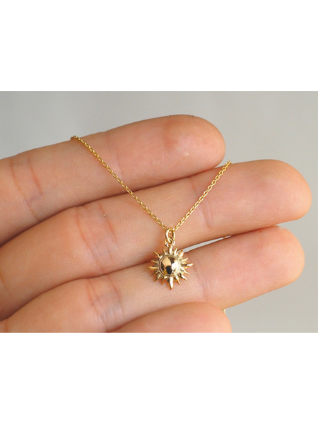ゴールドのサンモチーフトップを手のひらにのせて、小ぶりで上品なサイズ感がわかるネックレスのイメージ画像。
