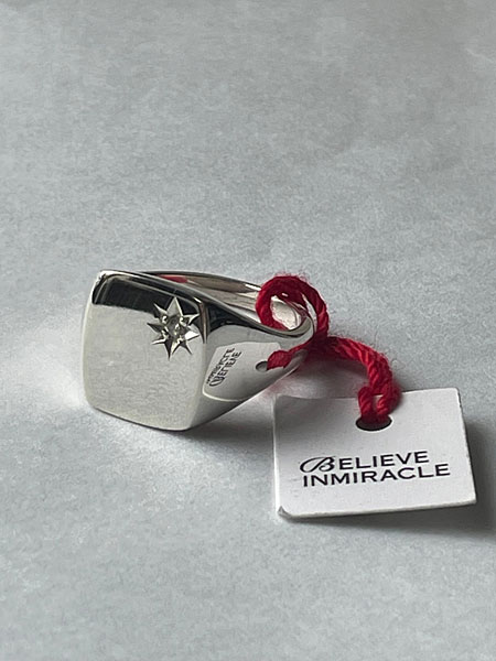 グレーの下地の上に置かれたシグネットリングが、シンプルな背景でより洗練された印象に見えるイメージ画像。