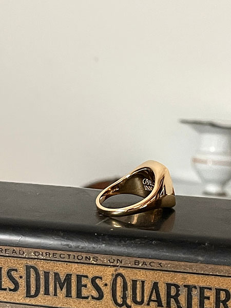 アメリカンな質感の台の上に置かれたリングを横から写し、フォルムの美しさが際立つ落ち着いた雰囲気の一枚。