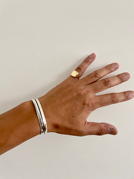 デザイナーが小指に着用したシグネットリングの手元アップで、ゴールドの上品な存在感が自然に馴染む様子。