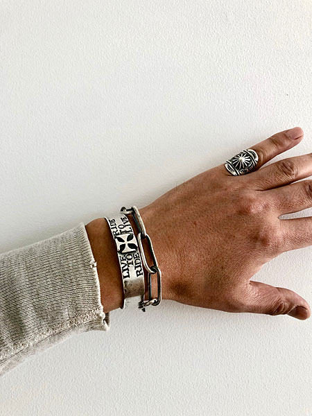 デザイナーが小指に着用し、存在感のあるリングがコーディネートに映える手元のアップ画像。