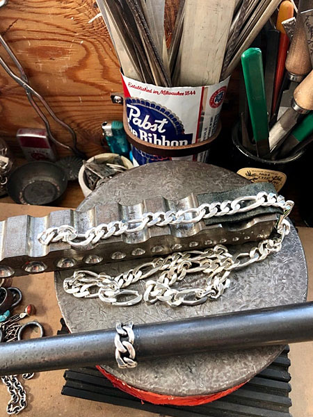 アトリエの作業台に置かれたフィガロチェーンのパーツが、これからリングになる工程を感じさせる制作風景画像。