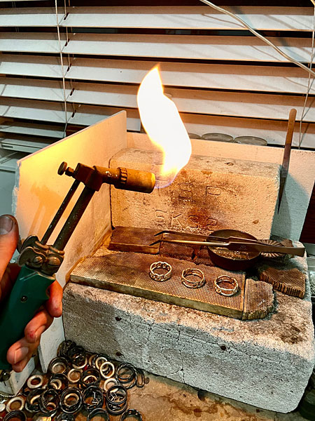 成形されたリングに火を入れている工程の様子を捉えた、アトリエでの制作シーンのカット。