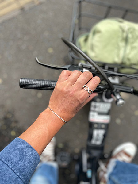 自転車に乗る日常の中で人差し指にリングを着用し、自然な雰囲気の中で映える手元のカット。