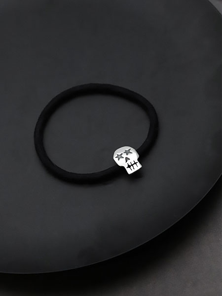 黒い丸い台の上にスカル コンチョ ヘアゴム ブレスレットを置いた、雰囲気のあるディスプレイ画像。