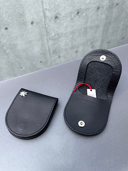 コンクリートの壁の前で閉じた状態と開いた状態のコインケースを並べ、使い方が分かる画像。