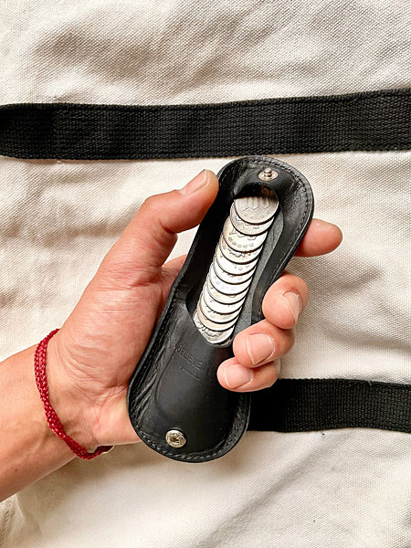 デザイナーがコインを入れた状態でコインケースを手に持ち、実際のサイズ感が分かるイメージ画像。