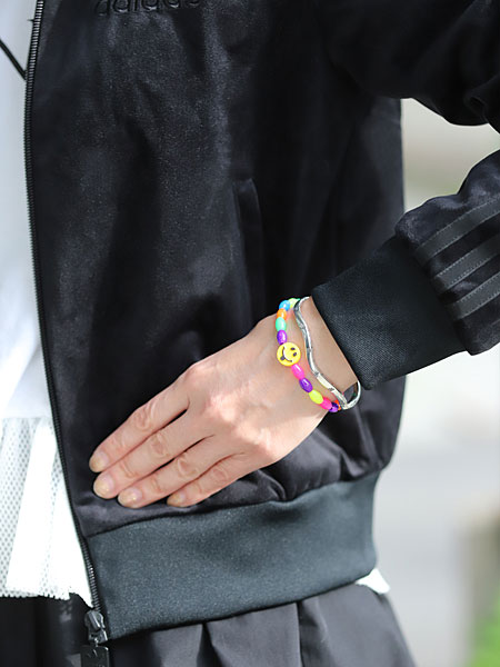 プラスチックビーズブレスレットと重ね付けした女性の手元で、スネークバングルが程よいアクセントになる着用イメージ。