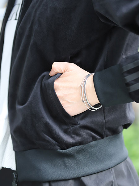 ワイヤーブレスレットと重ね付けした女性の手元で、細身のラインバングルが自然に馴染む着用イメージ。