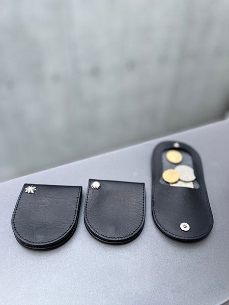 コンクリートの壁の前で星と丸のコインケースと開いた状態のものを並べた雰囲気のあるディスプレイ画像。