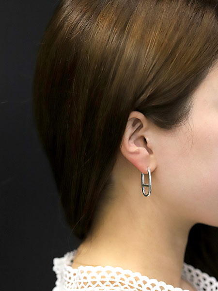 大ぶりながらフラットなフォルムですっきりと収まるアンカーフープピアスの女性着用画像。