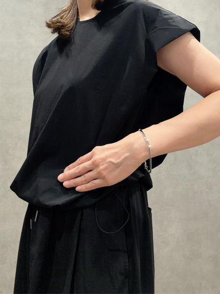 ブラックコーデの女性がゆったりと着用した、細身のIDブレスレットが手元に上品な抜け感を添える着用イメージ。