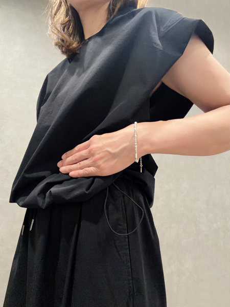 ブラックコーデの女性が着用した、細身のビーズブレスレットが手元に自然に馴染む上品な着用イメージ。