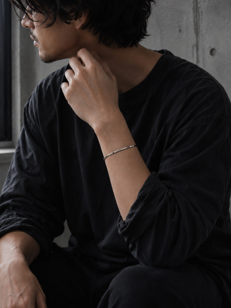 程よいボリューム感と立体的な凹凸が手元に自然と馴染み、スタイリッシュな印象を与える男性の着用画像。