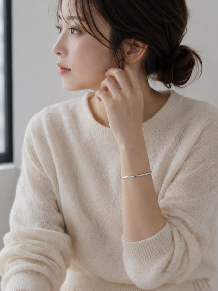 女性の手元に、すっきりとしたフォルムとつややかな光沢を持つカフバングルが上品になじむ着用画像。