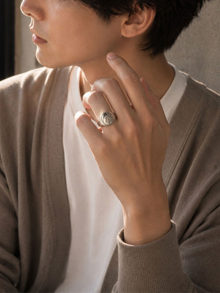 キレイめコーデの男性が薬指にバザーシグネットを着けた手元の着用画像。