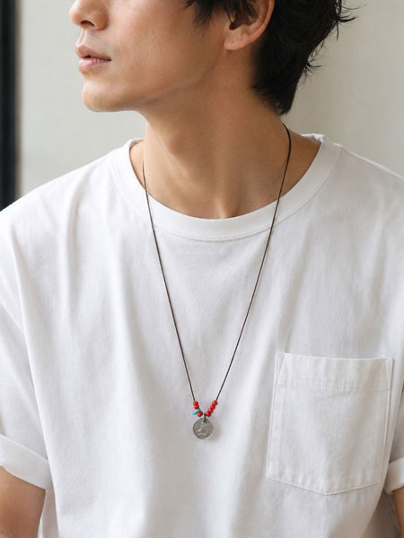 白Tシャツにあわせたロングネックレスを男性が身につけた着用画像。