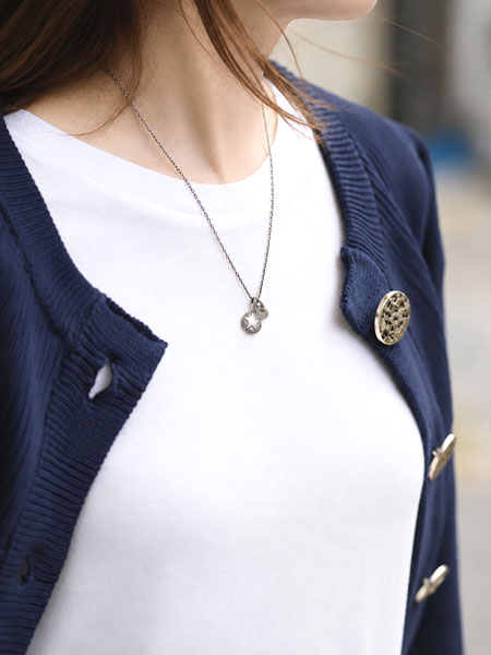 紺のカーディガンと白Tシャツに品よく馴染む女性の着用画像。