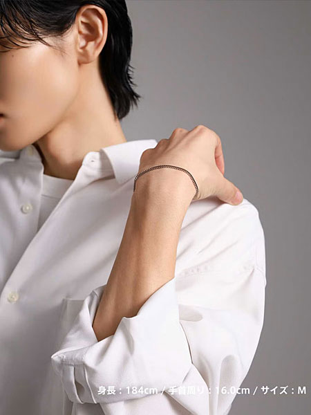 肩に手を添えた男性がシルバーチェーンブレスレットを着けた自然な着用写真。