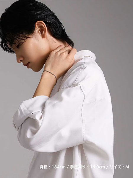 首元に手を添えた男性がシルバーチェーンブレスレットを着けた自然な着用写真。