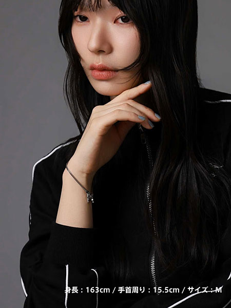 首元に手を添えた女性がシルバーブレスレットを着けた自然な着用写真。