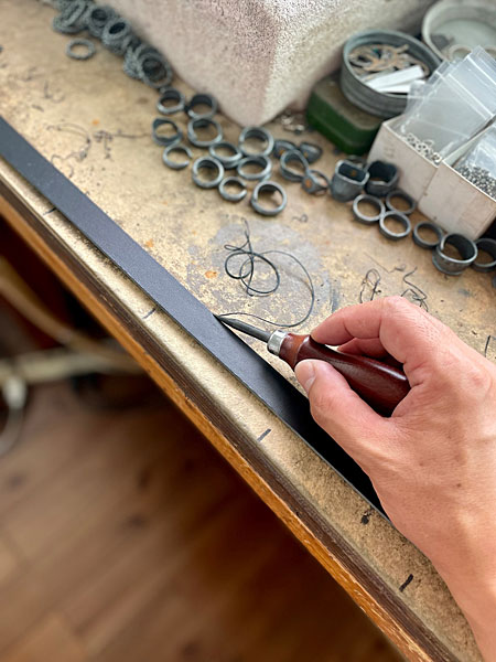 レザーベルトの側面を工具で綺麗にカットしているアトリエでの制作風景の画像。
