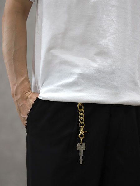 白いTシャツと黒いボトムスの腰もとにキーホルダーを合わせた男性の着用イメージ。