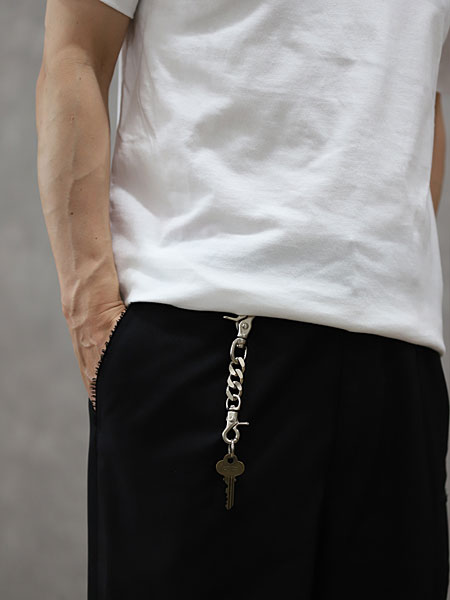 白Tシャツと黒のボトムスにマットホワイトのキーホルダーを合わせた男性の腰もとの着用イメージ。