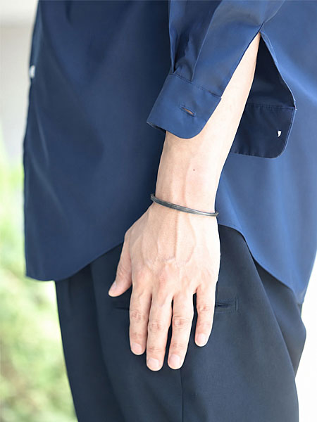ネイビーシャツとスラックス風のパンツにカフバングルを合わせた男性の着用イメージ。