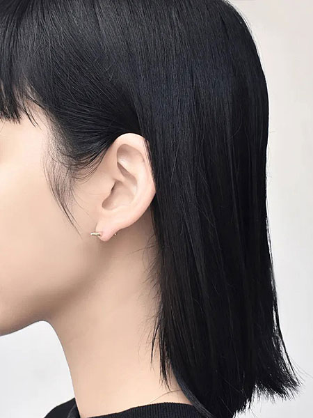縦型のフォルムが耳元でシャープに映え、スパイシーな印象を与えている女性のピアス着用画像。
